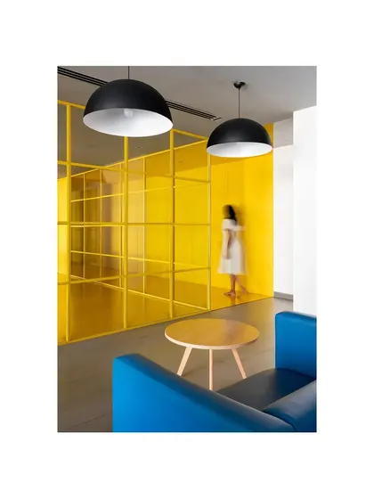 A lounge area in 'The Amber Encase' clubhouse, where a yellow-tinted glass grid separates the space while maintaining visual connection. The design uses a primary color palette of yellow, blue, and black to create a modern and graphic interior.