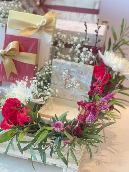 A close-up of the floral arrangement on the bridal snack hamper, with red carnations, white chrysanthemums, and baby's breath adding a touch of freshness and elegance.