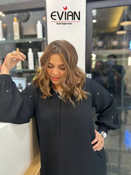 A happy client posing with her new look. The warm-toned balayage complements her skin tone perfectly, and the soft waves give her a chic, effortless style.