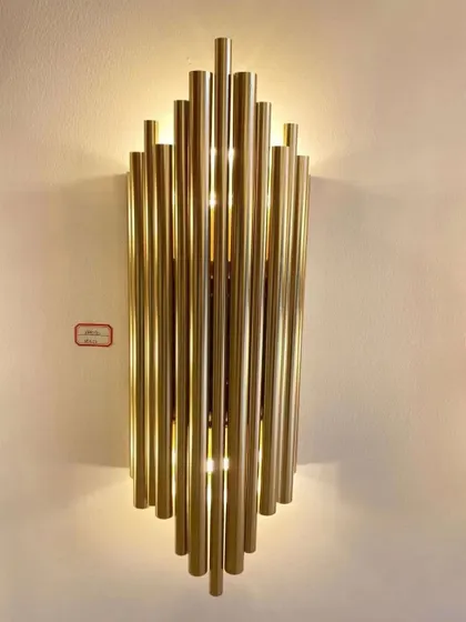A striking wall sconce made of staggered brass tubes. This fixture creates a bold, architectural statement while providing beautiful ambient light.