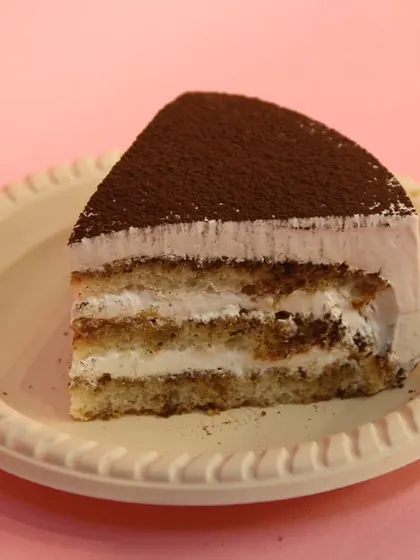 A slice of our classic Tiramisu. It features layers of coffee-soaked ladyfingers and creamy mascarpone, finished with a dusting of cocoa powder.