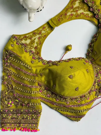 This lime green blouse is designed with a modern halter neck. The intricate embroidery along the neckline and sleeves adds a touch of traditional craftsmanship to a contemporary silhouette.