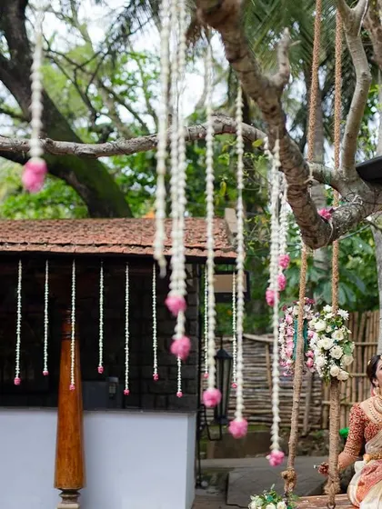 A couple on the swing, surrounded by hanging floral decorations, creates a whimsical and romantic scene.