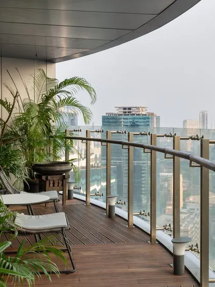 This curved balcony, featured in Polkadot Magazine, offers a panoramic view of the city. The design uses a simple wooden deck and comfortable seating, surrounded by plants, to create a green oasis in the sky.