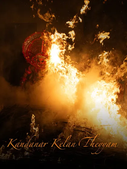 A dramatic shot of the Kandanar Kelan Theyyam emerging from the flames, a visual representation of his rebirth as a divine being. The text overlay shares the powerful folklore behind this fire ritual.