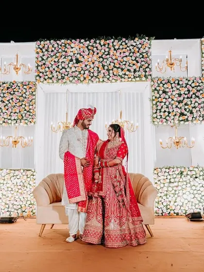 A grand reception stage with a backdrop of alternating floral panels and chandeliers, creating a look of pure opulence.