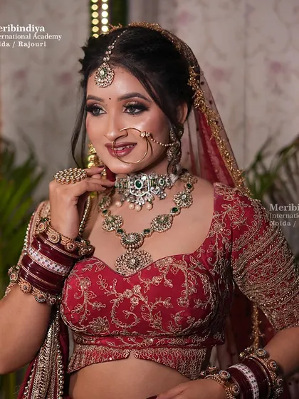 A classic red bridal lehenga look, with the hair styled in a traditional updo to perfectly hold the dupatta and jewelry.
