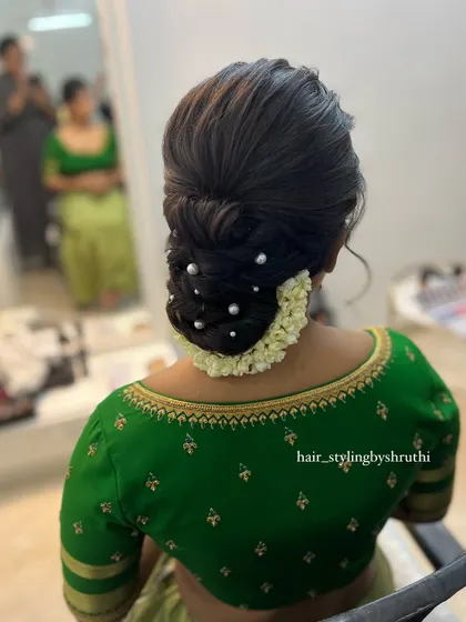 A textured low bun accented with pearls and a delicate arrangement of fresh flowers at the base. This style is both modern and traditional, making it suitable for various wedding events.