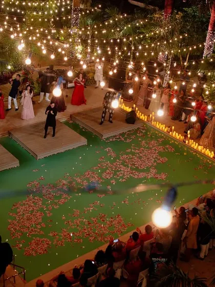 An epic sangeet setup over a pool in Goa, with the stage built on the water and the entire area illuminated by strings of fairy lights.