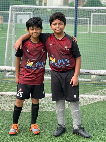 Two young players stand together, showcasing the bonds and friendships that are built through teamwork and shared passion for football.