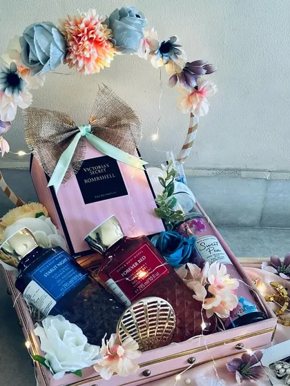 A luxury cosmetics and perfume hamper for the bride. This gift features premium brands, artfully arranged in a decorative basket with a floral halo and fairy lights.