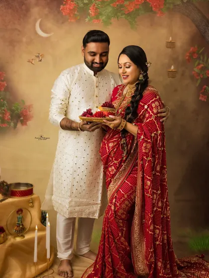 Celebrating love and tradition with a Karva Chauth themed maternity shoot. The couple shares a moment with the puja thali, set against a warm, festive backdrop that glows with affection.