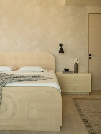 A detail of the bed and nightstand, showcasing the use of Movingue White veneer with its abstract patterns to create visual depth.