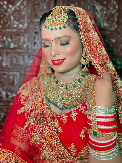 Every detail matters in a bridal look. This shot highlights the beautiful contrast between the red bridal attire, the green jewelry, and the carefully applied makeup.