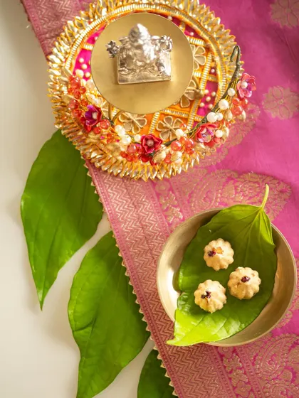 A traditional setup for Ganesh Chaturthi, featuring a silver Ganesha idol, modaks, and fresh betel leaves on a pink silk cloth. This image showcases my ability to style culturally significant scenes with elegance and authenticity.