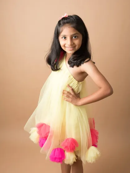A young girl poses confidently in a bright and colorful dress. A beautiful portrait that captures her vibrant personality.
