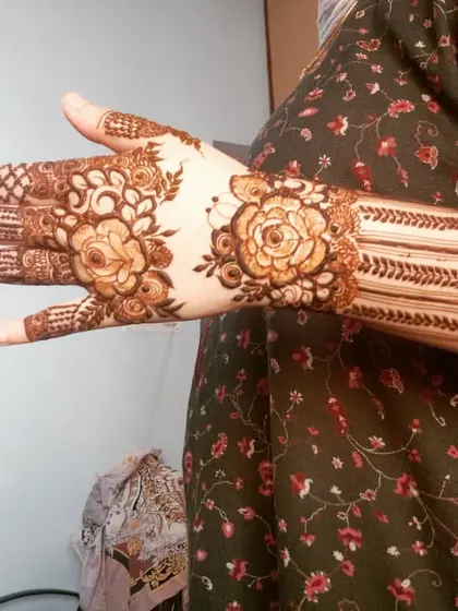 A designer mehndi with a unique band style. The rose motifs and striped patterns create a modern and stylish look.