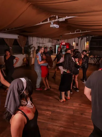 A wide shot of the dance floor filled with costumed dancers during the Halloween social.
