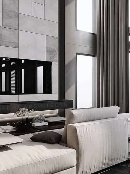 In this residence, we created a double-height living space with a monolithic grey marble feature wall for the television and fireplace. The monochromatic palette is softened by a plush white sectional sofa and abundant natural light from tall windows.