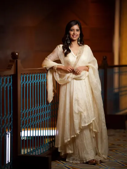 A full-length view that highlights the flowing silhouette of the traditional dress. The elegant setting and happy expression make this a beautiful event photograph.