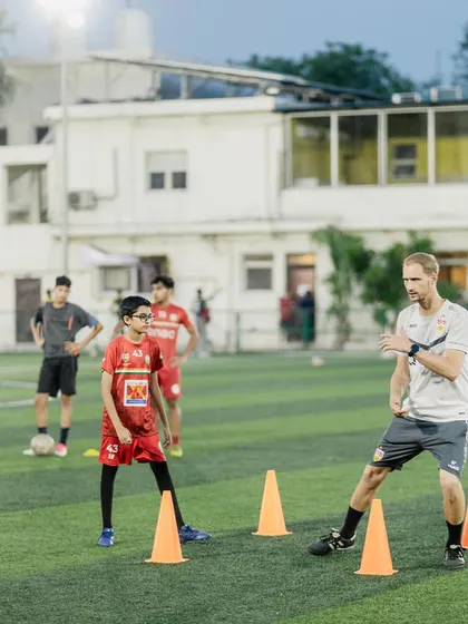A VfB Stuttgart coach demonstrates a cone drill, focusing on agility and ball control. Our players learn by watching and then doing, mastering the same exercises used to train youth players in Germany's top academies.
