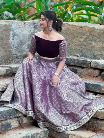 A candid shot of a client enjoying her event in the purple off-shoulder crop top and brocade skirt. This shows the outfit's comfort and style in a real-world setting.