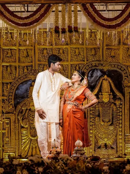 A grand stage photo from a Pondicherry wedding, with the couple framed by an elaborate, traditional golden backdrop.