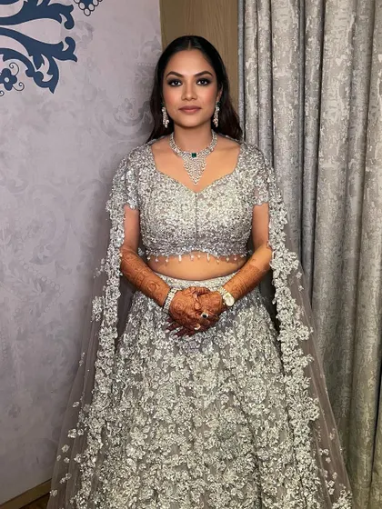 A full view of this timeless cocktail look. The smokey eyes are the star, balanced by a neutral lip and radiant skin, letting her shine in her beautiful silver lehenga.