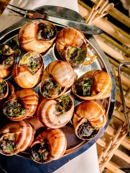A platter of escargots served with traditional tongs, ready for guests to enjoy.