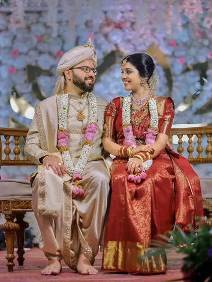 A classic, elegant portrait of the couple seated on the wedding dais, showcasing their beautiful coordinated outfits.
