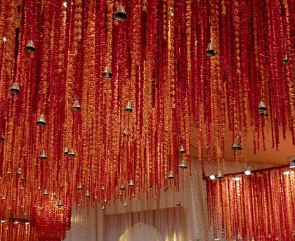 A closer look at the ceiling of the 'Lal Bagh' mandap, where thousands of hand-painted shola flowers were strung with mauli threads and tiny bells, creating a cascading floral symphony.