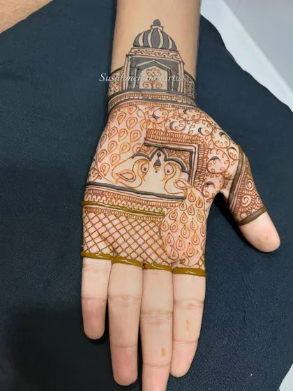 The design in progress, with the checkerboard (jaali) pattern being filled in around the central peacock motif.