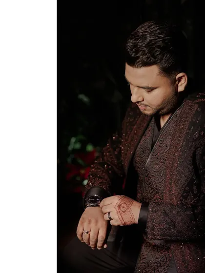 The final details matter. Here, the groom adjusts his watch, showing off the full Sangeet ensemble with its detailed embroidery and sharp tailoring.