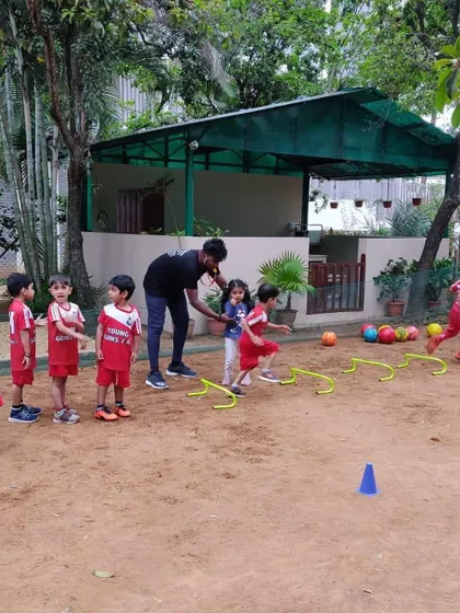 A coach assists a child with a hurdle drill in a sandpit, adding a different sensory and physical challenge. We adapt our training to various environments to keep it exciting.
