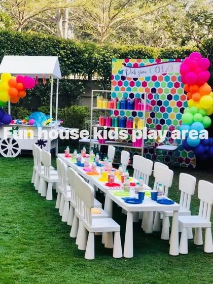 Our white tables and chairs set up as a vibrant art and craft station. The clean white furniture provides the perfect canvas for colorful activities, complete with a rainbow balloon garland and a cart full of supplies.