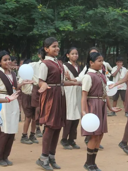 Young girls participate in a balloon game, their faces full of concentration and fun. These activities are designed to be inclusive and engaging for everyone.