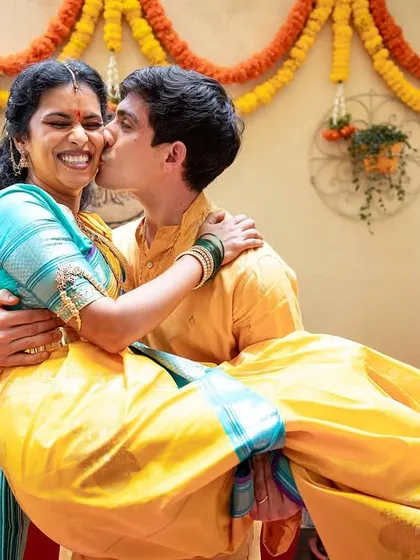 A playful and romantic moment from a Haldi celebration, with the groom lifting his bride, surrounded by traditional marigold decor.
