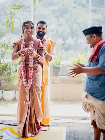 The joy of the ceremony is infectious. Here, the couple shares a happy moment with their priest, framed by the natural light and greenery of our decor.