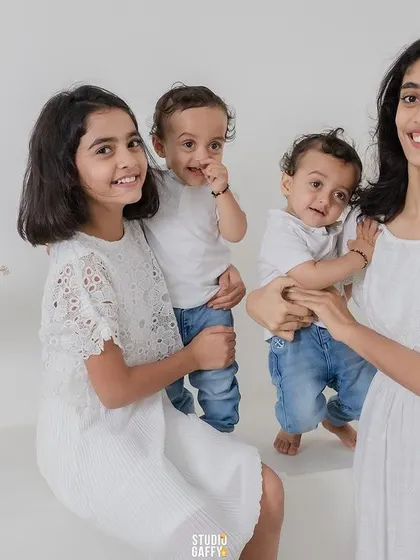 A beautiful portrait of three sisters and a baby brother, all dressed in white, showcasing a lovely sibling bond.