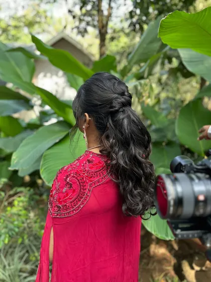 A behind-the-scenes shot of this beautiful half-up, half-down hairstyle with soft curls. This versatile style is perfect for a welcome lunch or mehendi event.