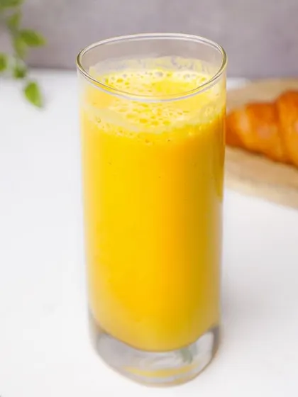A tall glass of fresh mango smoothie, presented in a bright, clean style perfect for a breakfast menu.