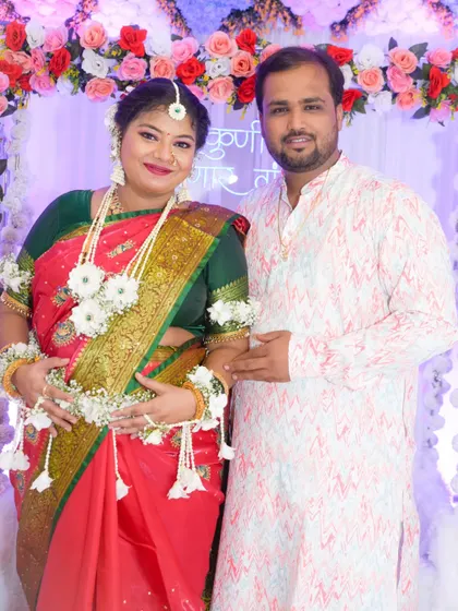 A full-length portrait of the couple, showcasing their coordinated outfits and the festive atmosphere of the baby shower.