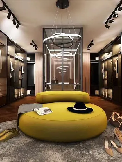 An expansive and luxurious walk-in closet featuring glass-paneled wardrobes with internal lighting, a central seating ottoman, and ample shelving. This custom closet design provides exceptional organization and a high-end boutique feel.