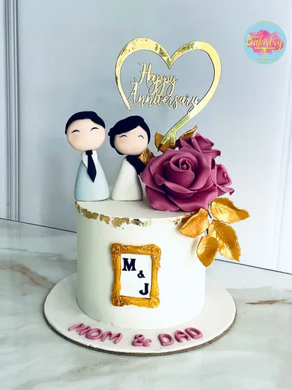 Love is in the details. An anniversary cake for "Mom & Dad" with adorable couple figurines and a large pink rose.