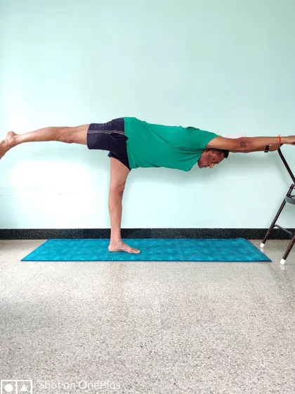This is Veerabhadrasana 3 (Warrior 3 Pose) performed with the support of a chair. The chair allows you to hold the asana, focus on extending the spine and back leg, and build strength without compromising the alignment. This is how we make advanced postures accessible and safe for practice at home.