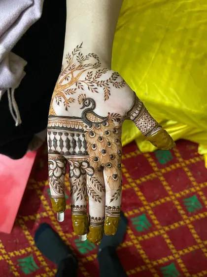 A simple yet stunning peacock design for a guest. The peacock's feathers flow beautifully across the hand, making it a standout piece.