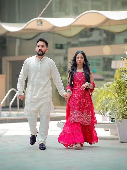 A full-length shot of the couple walking by the pool during their engagement photoshoot.