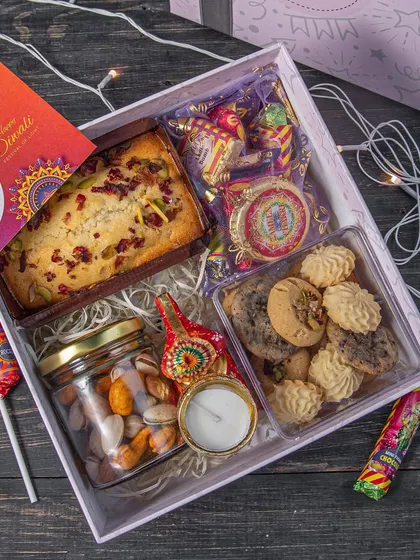Our Diwali Indulgence Hamper is a step up, featuring a tea cake, dry fruits, gourmet cookies, cracker chocolates, and a handcrafted diya. It's a complete festive package.