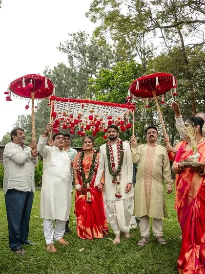 The bride and groom's grand procession, surrounded by family holding traditional red umbrellas.