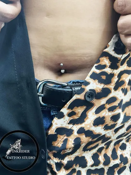 A stylish navel piercing shown with a fashionable outfit. This body modification is a great form of self-expression.